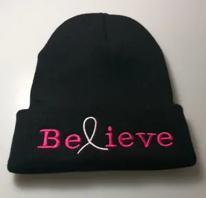 Detail of Believe embroidery and pink ribbon on a black ribbed knit beanie hat