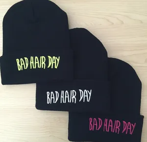 Détail de la broderie BAD HAIR DAY sur des bonnets noirs en jaune, blanc et rose vif