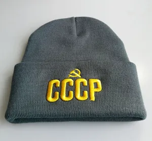 Detail der grauen Strickmütze mit gelber CCCP-Stickerei und Hammer-und-Sichel-Symbol