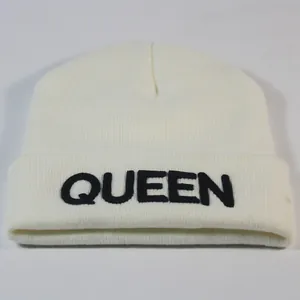 Detailansicht der schwarzen QUEEN Stickerei auf der weißen Winter-Strickmütze