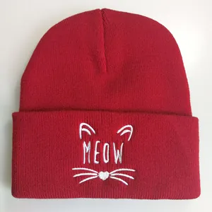 Rote Strickmütze mit Meow-Stickerei und Katzenmotiven auf weißem Hintergrund