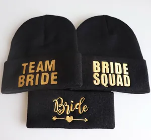 Detail von drei schwarzen Mützen mit goldener Team Bride und Bride Squad Stickerei