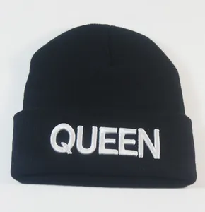 Nahaufnahme der weißen QUEEN-Stickerei auf einer schwarzen Strickmütze für Damen