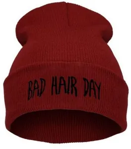 Gros plan de la broderie Bad Hair Day sur un bonnet en maille rouge bordeaux