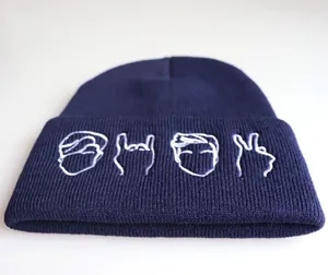 Dettaglio del berretto in maglia blu scuro con ricamo bianco minimalista e trama fine