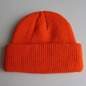 Nahaufnahme der leuchtend orangefarbenen Strickmütze mit vertikaler Rippenstruktur und Umschlag