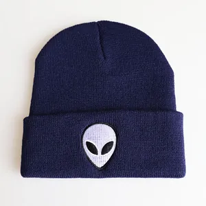 Detaillierte Nahaufnahme der Alien-Kopf-Stickerei auf der marineblauen Strickmütze