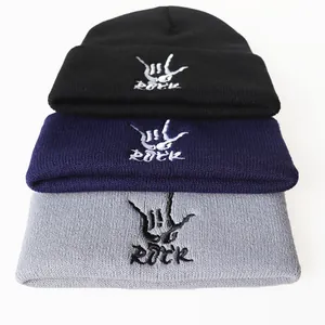 Stack of black, blue, and grey ROCK embroidered knit beanies in minimalist style