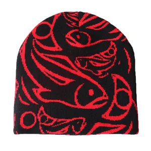 Detalle del gorro de punto negro y rojo con patrones abstractos de peces y líneas geométricas