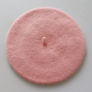 Gros plan d'un béret rose en laine avec une petite tige, montrant la texture feutrée