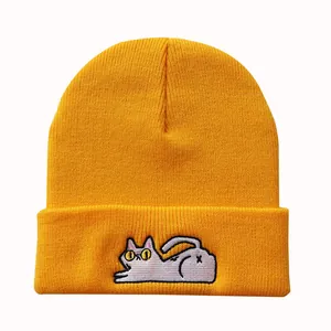 Nahaufnahme der gelben Strickmütze mit lustiger Katzenbestickung auf dem umgeschlagenen Rand