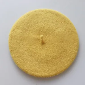 Vue de dessus du béret en feutre de laine jaune montrant la texture lisse et la queue