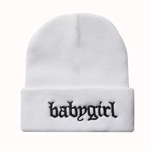 Detailaufnahme der Babygirl-Stickerei auf weißer Strickmütze mit gotischer Schrift
