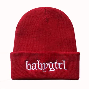 Detail der weißen babygirl Stickerei auf einer dunkelroten Strickmütze mit Rippstruktur