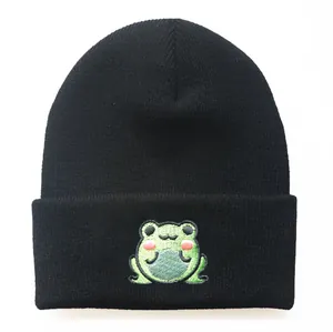 Detailansicht der niedlichen grünen Froschstickerei auf der schwarzen Strickmütze