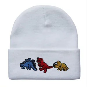 Detailansicht von drei bunten Cartoon-Dinosaurier-Stickereien auf weißer Beanie