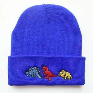 Detaillierte Nahaufnahme bunter Dinosaurier-Stickereien auf einer blauen Strickmütze