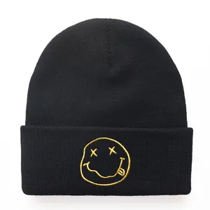 Classic 90s black knit beanie with yellow grunge smiley face embroidery on white background
