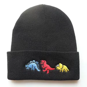 Detailaufnahme der bunten Dinosaurier-Stickerei auf einer schwarzen Strickmütze