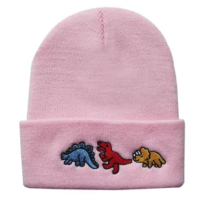 Detailansicht der rosa Strickmütze mit drei bunten Cartoon-Dinosaurier-Stickereien