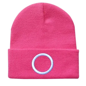 Detail einer leuchtend pinkfarbenen Strickmütze mit weißem Kreis-Stickmuster vorne