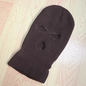 Textura de punto detallada de un pasamontañas marrón de tres agujeros para invierno frío