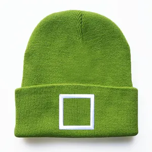 Detail einer grünen Strickmütze mit weißer quadratischer Bestickung und Rippenstruktur