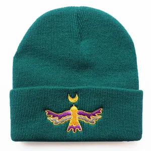 Deep green knit beanie with detailed colorful bird and crescent moon embroidery on front