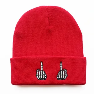 Detail einer roten Strickmütze mit weißer Stickerei einer Skelett-Mittelfinger-Geste