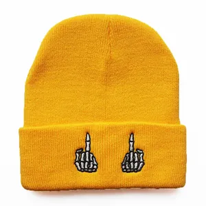 Detail der gelben Strickmütze mit weißer Skeletthand-Stickerei auf dem Aufschlag