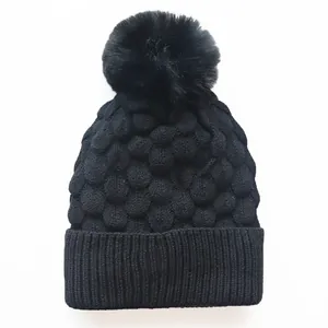 Schwarze Strickmütze mit Kunstfell-Bommel und strukturierter Textur für Winterwärme