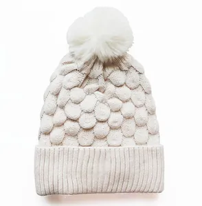 Nahaufnahme des groben Strickmusters und weißen Kunstfellbommel an der Strickmütze