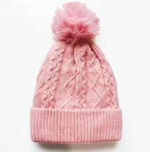 Nahaufnahme der rosa Zopfmuster-Mütze mit flauschigem Bommel und breitem Rippsaum