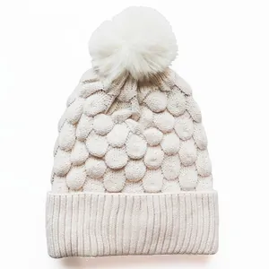 Beigefarbene Strickmütze mit Bommel und strukturiertem Schuppenmuster für den Winter