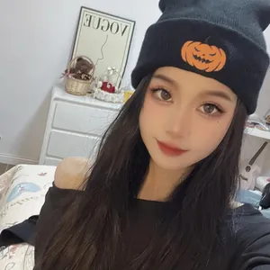 Detail einer schwarzen Strickmütze mit Halloween Kürbis-Aufnäher an einem Modell