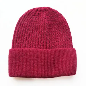 Nahaufnahme der rosaroten Strickmütze mit detaillierter Zopfmuster-Textur und warmem Garn
