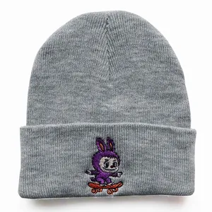 Close-up of grey knit beanie featuring a purple cartoon embroidery on the folded cuff