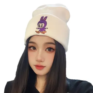 White knit beanie with purple cartoon rabbit embroidery worn by female model