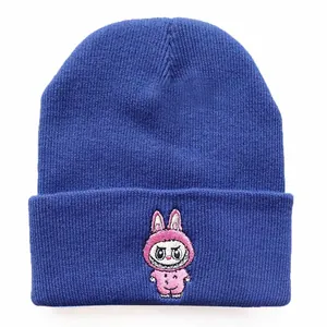 Detail of a dark blue knitted beanie featuring a pink cartoon character embroidery