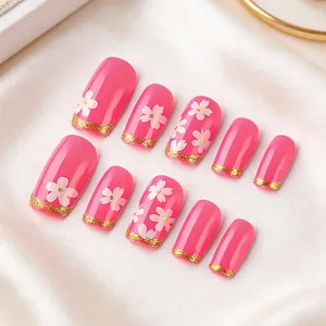 Faux ongles roses avec fleurs de cerisier blanches et pointes françaises pailletées dorées