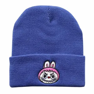 Detailed embroidery of a cartoon monster on a navy blue ribbed knit beanie hat
