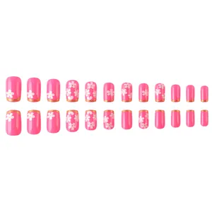 Faux ongles roses avec motifs de fleurs de cerisier et bords dorés pailletés