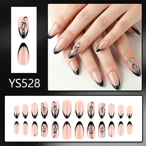 Medium almond press-on nails with black French tips, floral patterns and small rhinestones