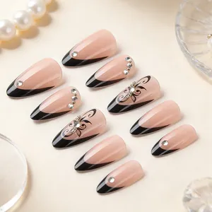 Almond shaped press-on nails with black French tips, rhinestone accents, and floral patterns