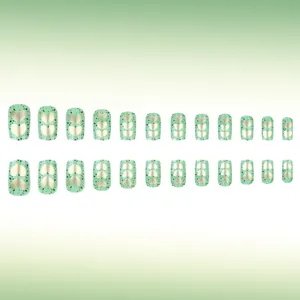 Detailed set of 24 mint green press-on nails with golden hearts and emerald splatter pattern