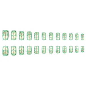 Short square press-on nails in avocado green with gold hearts and speckled patterns
