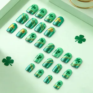 Close-up of St. Patrick's Day green glitter press-on nails with clover and gold patterns