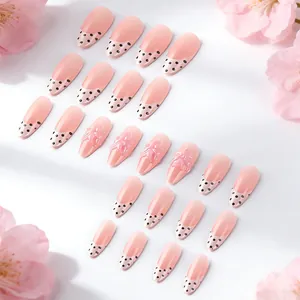 Dettaglio di 24 unghie finte rosa a goccia con pois neri e decorazioni floreali in rilievo