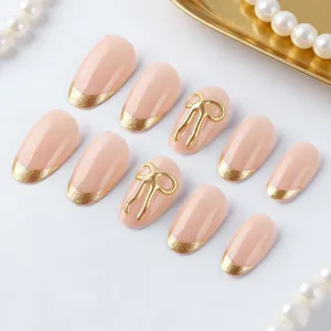 French nude pink press-on nails with gold French tips and 3D bow accents