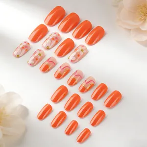 Detailed view of glossy orange and daisy flower press-on nails set with glitter accents